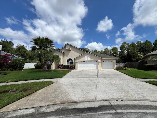 view of front facade with a garage, fence, a front yard, stucco siding, and concrete driveway