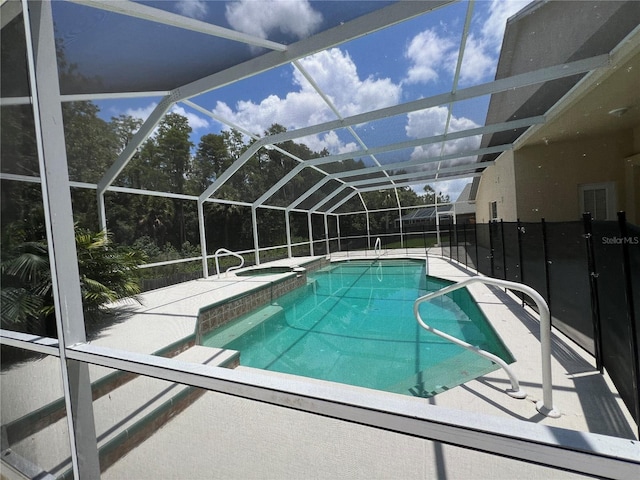 view of pool featuring glass enclosure, a pool with connected hot tub, and a patio area