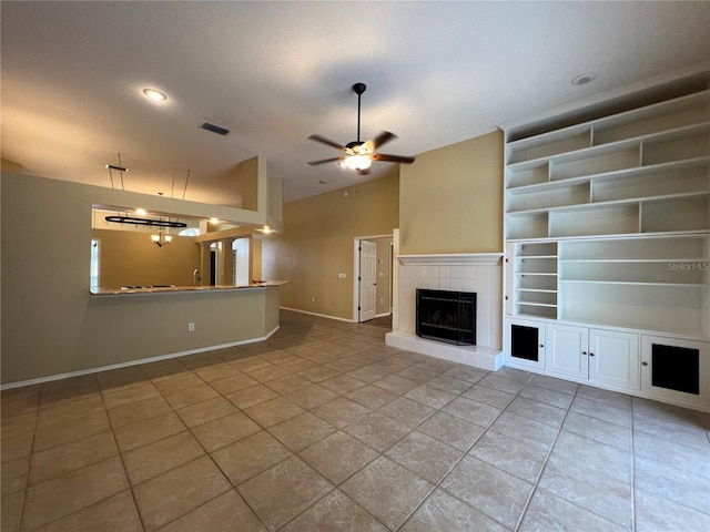 unfurnished living room featuring a ceiling fan, visible vents, a fireplace, vaulted ceiling, and tile patterned floors