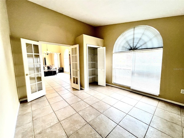 spare room with light tile patterned floors, an inviting chandelier, and french doors