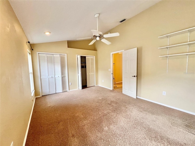 unfurnished bedroom featuring carpet flooring, multiple closets, baseboards, lofted ceiling, and visible vents