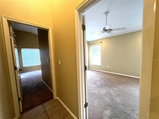 corridor featuring baseboards and carpet flooring