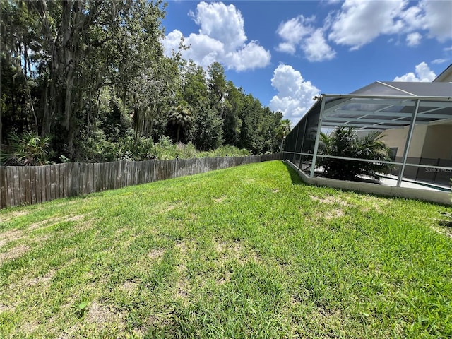 view of yard featuring glass enclosure and fence