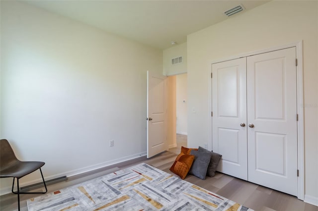 bedroom featuring baseboards, visible vents, wood finished floors, and a closet