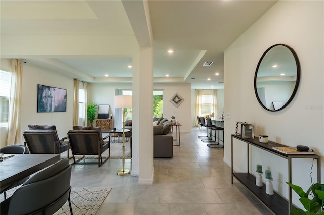living room featuring visible vents, recessed lighting, a raised ceiling, and baseboards