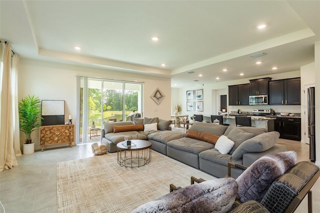 living area featuring visible vents, recessed lighting, a raised ceiling, and light tile patterned flooring