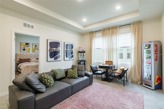 living area featuring a tray ceiling, recessed lighting, light tile patterned flooring, and visible vents