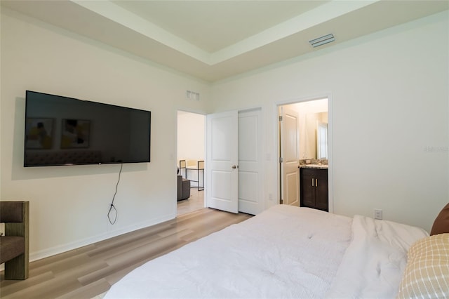 bedroom with visible vents, baseboards, connected bathroom, and wood finished floors