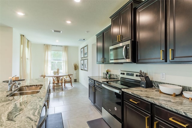 kitchen featuring light stone countertops, a sink, stainless steel appliances, recessed lighting, and visible vents