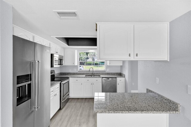 1913 Poinsetta Ln, Maitland, FL 32751 - kitchen featuring appliances with stainless steel finishes, a sink, light stone countertops, and a peninsula