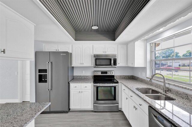 1913 Poinsetta Ln, Maitland, FL 32751 - kitchen with appliances with stainless steel finishes, a sink, a raised ceiling, light stone countertops, and white cabinets