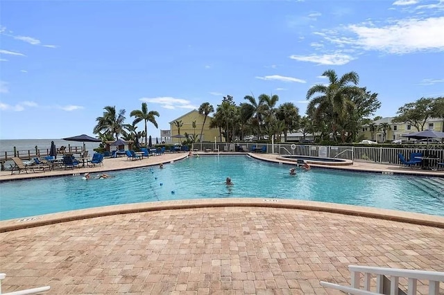 community pool featuring a patio area, a hot tub, and fence