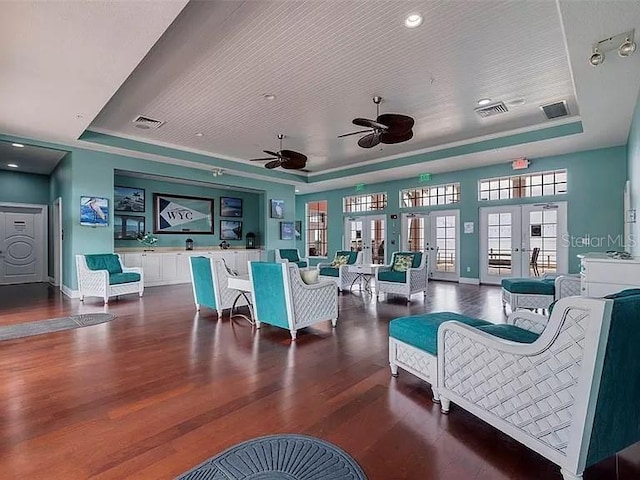 living area featuring a tray ceiling, visible vents, and ceiling fan
