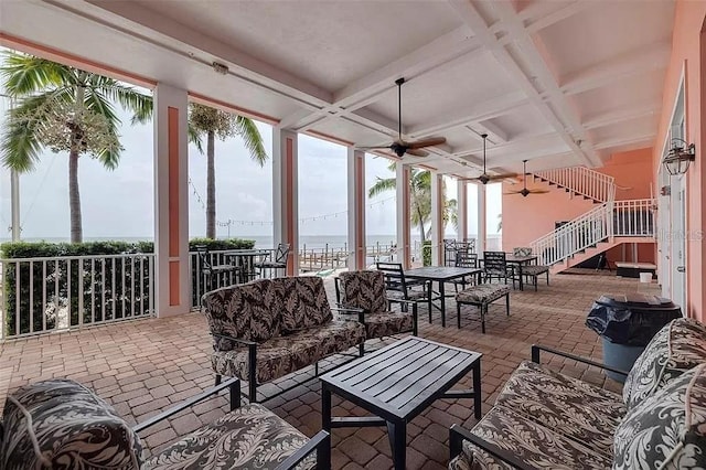 exterior space with coffered ceiling, a water view, outdoor lounge area, and a ceiling fan