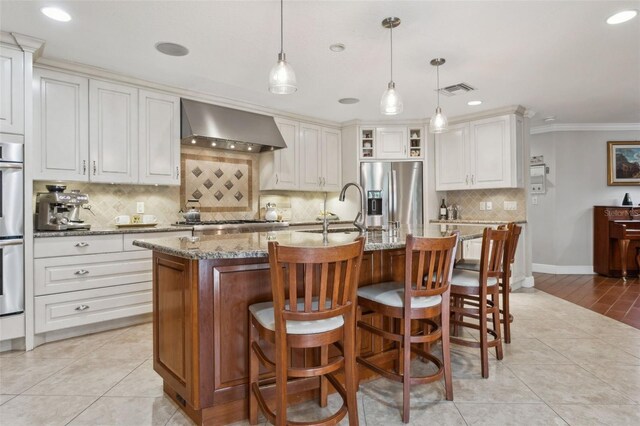 3906 Floyd Rd, Tampa, FL 33618 - kitchen featuring stainless steel appliances, wall chimney exhaust hood, a sink, decorative backsplash, and light stone countertops