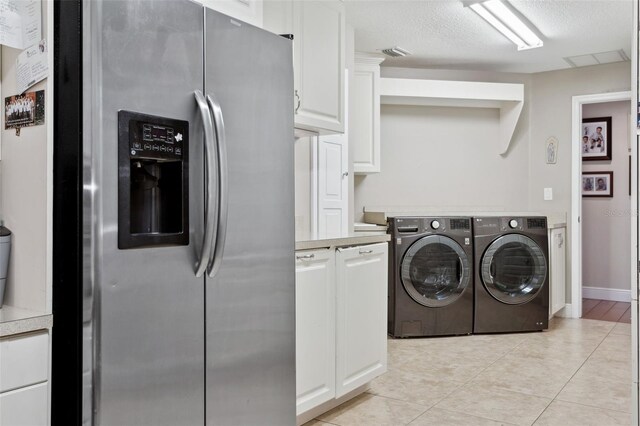 3906 Floyd Rd, Tampa, FL 33618 - laundry area featuring independent washer and dryer, light tile patterned floors, cabinet space, a textured ceiling, and baseboards