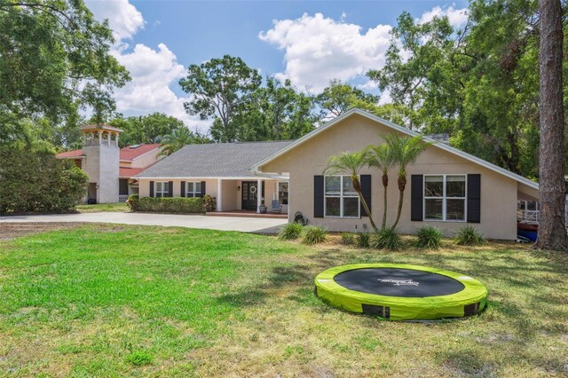 3906 Floyd Rd, Tampa, FL 33618 - view of front of home featuring a trampoline, a front lawn, stucco siding, and concrete driveway