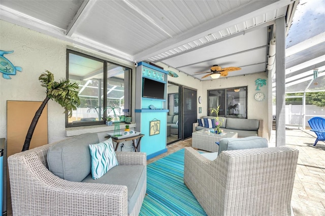 sunroom featuring ceiling fan, an outdoor living space, and beamed ceiling