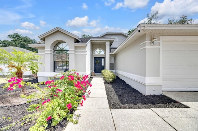 doorway to property featuring an attached garage and stucco siding