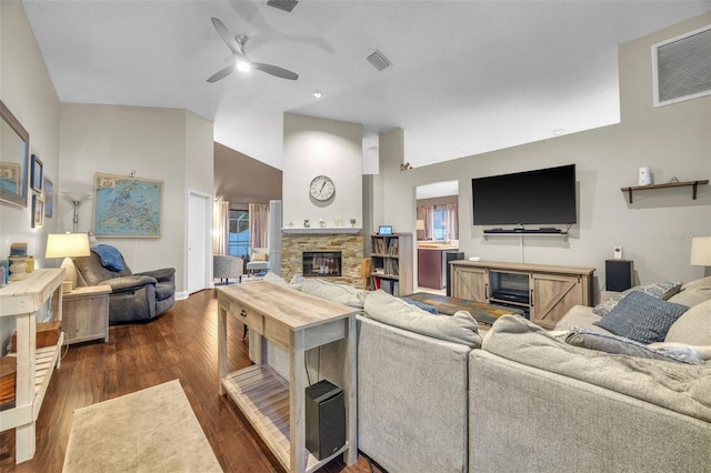 living room with a stone fireplace, a ceiling fan, dark wood-type flooring, and visible vents