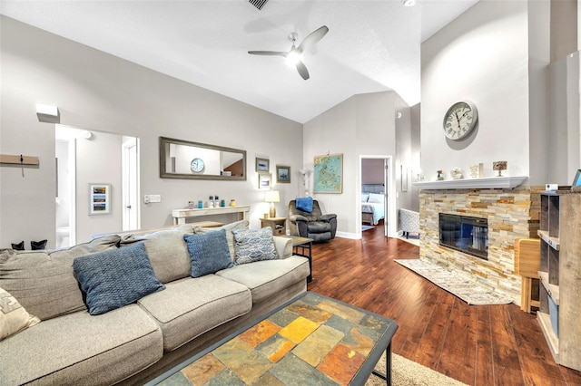 living area featuring high vaulted ceiling, ceiling fan, a stone fireplace, and wood finished floors