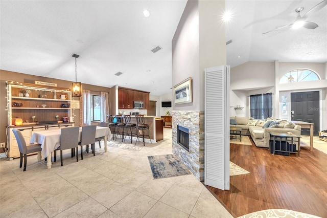 living area with visible vents, ceiling fan, a wealth of natural light, and high vaulted ceiling