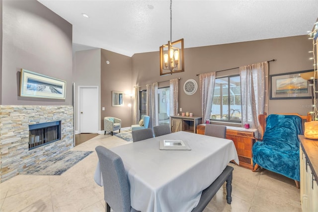 dining area with a textured ceiling, a fireplace, a notable chandelier, a high ceiling, and light tile patterned flooring