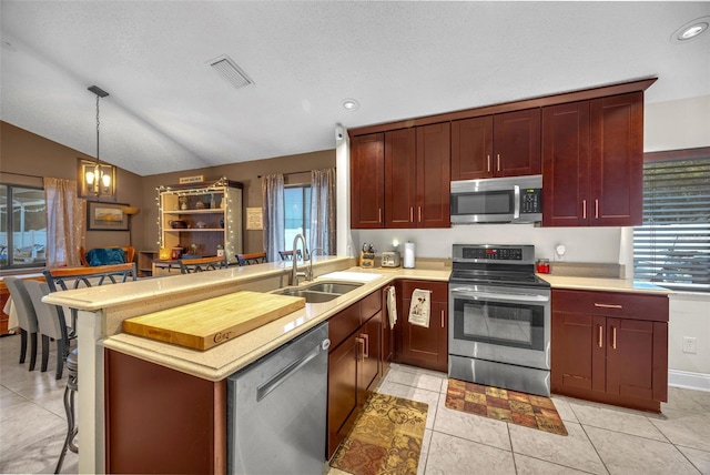 kitchen featuring appliances with stainless steel finishes, a sink, light countertops, a peninsula, and visible vents