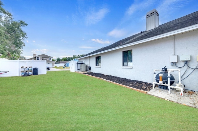 view of yard with central AC and fence