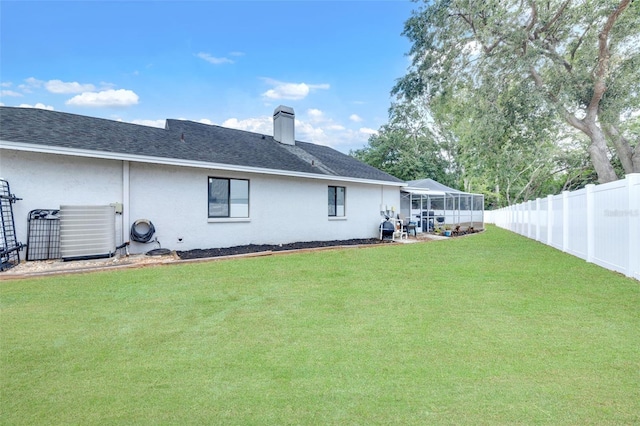 back of property with fence private yard, stucco siding, a chimney, a shingled roof, and a yard