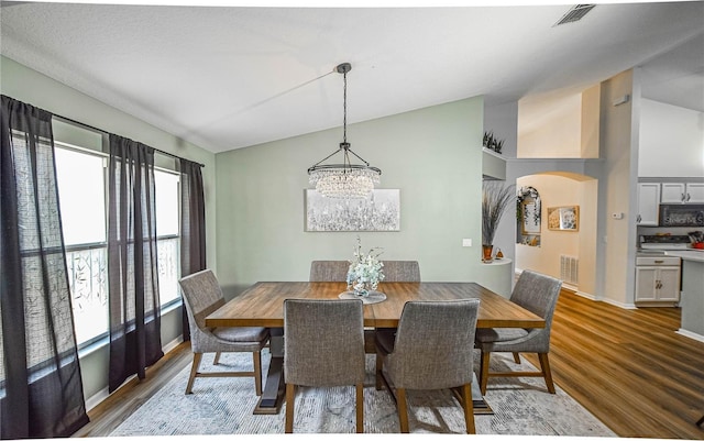 2604 Clareside Dr, Valrico, FL 33596 - dining area featuring wood finished floors, arched walkways, a chandelier, vaulted ceiling, and baseboards