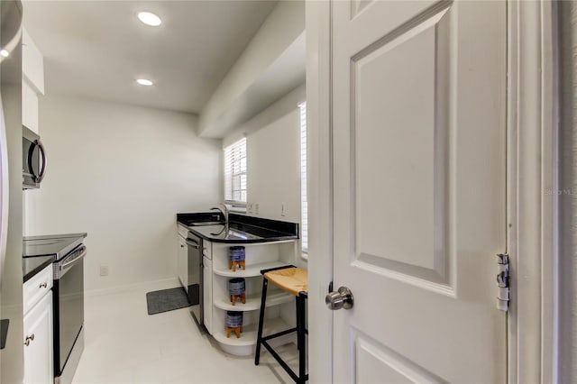 1115 Rue Des Chateaux Unit 2B, South Pasadena, FL 33707 - kitchen featuring a sink, baseboards, stainless steel appliances, recessed lighting, and white cabinetry