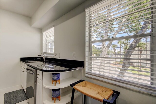 1115 Rue Des Chateaux Unit 2B, South Pasadena, FL 33707 - kitchen with stainless steel dishwasher, open shelves, a sink, white cabinets, and a peninsula