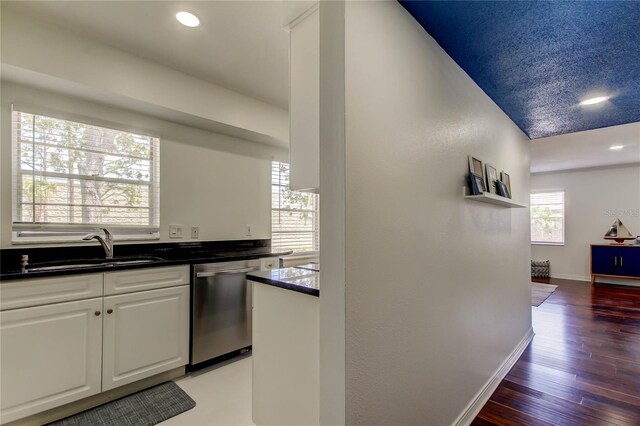 1115 Rue Des Chateaux Unit 2B, South Pasadena, FL 33707 - kitchen featuring stainless steel dishwasher, dark countertops, light wood-type flooring, white cabinets, and a sink