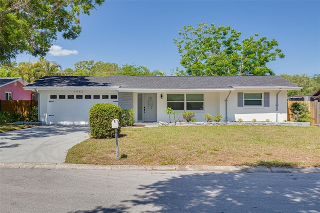 ranch-style house featuring a garage, a front lawn, fence, and driveway