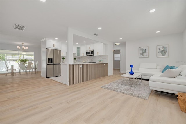 living room featuring recessed lighting, visible vents, light wood finished floors, and a notable chandelier