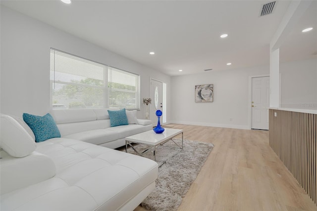 living room with recessed lighting, light wood finished floors, baseboards, and visible vents