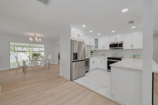 kitchen featuring light stone countertops, baseboards, white cabinetry, a sink, and stainless steel appliances