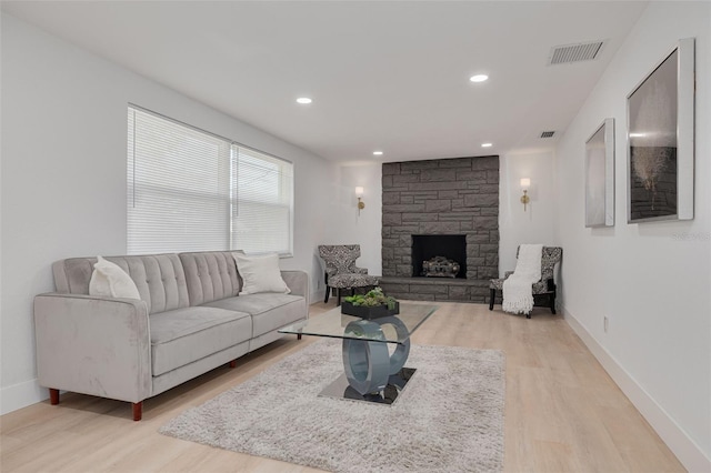 living room featuring visible vents, light wood-style flooring, baseboards, and a fireplace