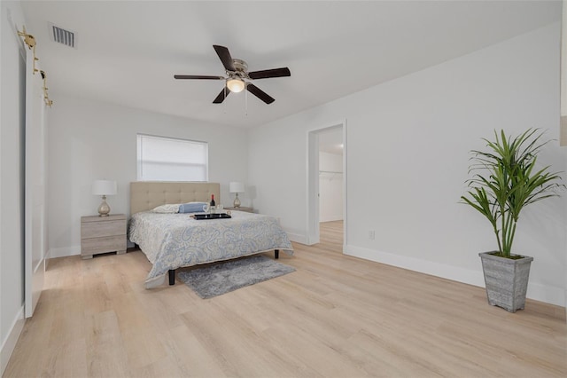 bedroom with visible vents, baseboards, a spacious closet, a ceiling fan, and light wood finished floors