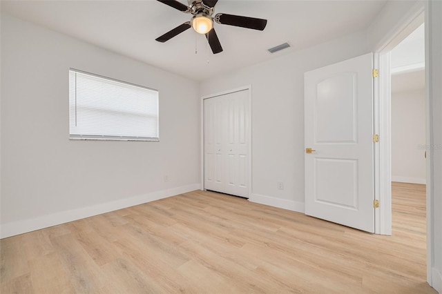 unfurnished bedroom with light wood-style flooring, a ceiling fan, baseboards, visible vents, and a closet