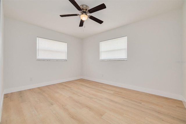 spare room with baseboards, a ceiling fan, wood finished floors, and a wealth of natural light