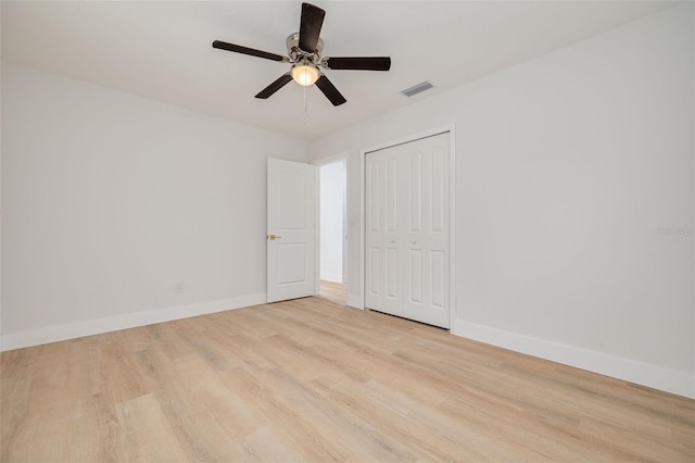 unfurnished bedroom featuring baseboards, a closet, wood finished floors, and visible vents