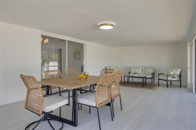 dining area with brick wall and light wood-style floors