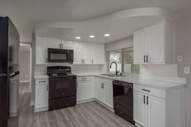 3601 Grayton Dr, New Port Richey, FL 34652 - kitchen featuring black appliances, a sink, tasteful backsplash, white cabinets, and light wood-style floors