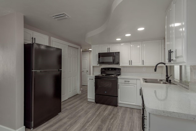 3601 Grayton Dr, New Port Richey, FL 34652 - kitchen featuring black appliances, a sink, white cabinets, recessed lighting, and light wood-type flooring