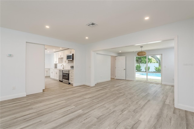 1152 Jackmar Rd, Dunedin, FL 34698 - unfurnished living room featuring light wood-style floors, recessed lighting, and baseboards