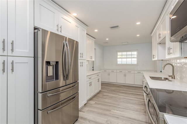 1152 Jackmar Rd, Dunedin, FL 34698 - kitchen with appliances with stainless steel finishes, a sink, white cabinets, recessed lighting, and light wood finished floors