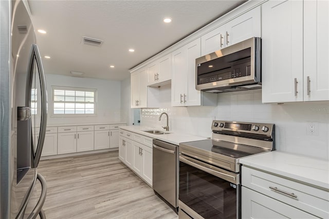 1152 Jackmar Rd, Dunedin, FL 34698 - kitchen with appliances with stainless steel finishes, a sink, white cabinets, light countertops, and recessed lighting