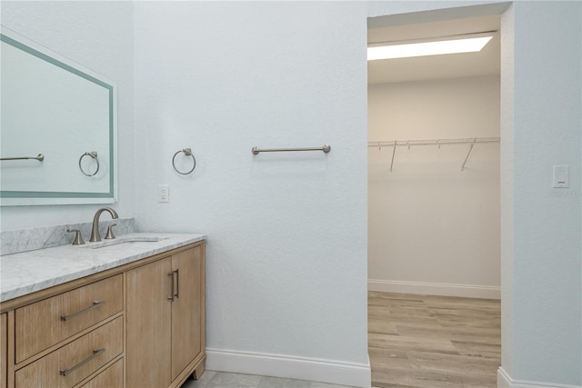 1152 Jackmar Rd, Dunedin, FL 34698 - bathroom featuring baseboards, vanity, a spacious closet, and wood finished floors